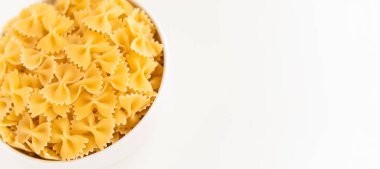 Çiğ pişmemiş Farfalle makarna makarna makarna beyaz kâse ahşap arka plan fesleğen domates pesto sosu ev yapımı İtalyan yemeği organik buğday vegan spagetti sağlıklı bir yemek için