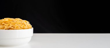 Çiğ pişmemiş Farfalle makarna makarna makarna beyaz kâse ahşap arka plan fesleğen domates pesto sosu ev yapımı İtalyan yemeği organik buğday vegan spagetti sağlıklı bir yemek için