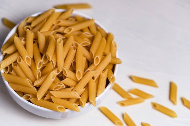 Beyaz arka planda bir kasede çiğ pişmemiş makarna. Fesleğen domates pesto sosu için iyi. Ev yapımı İtalyan yemeği. Biyolojik, organik, vejetaryen, sağlıklı bir yemek için spagetti.