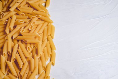 Beyaz arka planda bir kasede çiğ pişmemiş makarna. Fesleğen domates pesto sosu için iyi. Ev yapımı İtalyan yemeği. Biyolojik, organik, vejetaryen, sağlıklı bir yemek için spagetti.