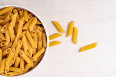 Beyaz arka planda bir kasede çiğ pişmemiş makarna. Fesleğen domates pesto sosu için iyi. Ev yapımı İtalyan yemeği. Biyolojik, organik, vejetaryen, sağlıklı bir yemek için spagetti.