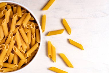 Beyaz arka planda bir kasede çiğ pişmemiş makarna. Fesleğen domates pesto sosu için iyi. Ev yapımı İtalyan yemeği. Biyolojik, organik, vejetaryen, sağlıklı bir yemek için spagetti.