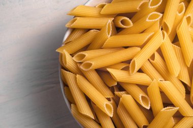 Beyaz arka planda bir kasede çiğ pişmemiş makarna. Fesleğen domates pesto sosu için iyi. Ev yapımı İtalyan yemeği. Biyolojik, organik, vejetaryen, sağlıklı bir yemek için spagetti.