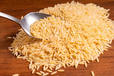 Çiğ pişmemiş Orza Risoni makarna makarna makarna beyaz kase ahşap arka plan fesleğen domates pesto sosu ev yapımı İtalyan yemeği tam buğday vegan spagetti sağlıklı bir yemek için