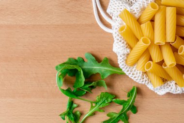 Çiğ pişmemiş Tortiglioni makarna makarna makarna beyaz kase ahşap arka plan fesleğen domates pesto sosu ev yapımı İtalyan yemeği tam buğday vegan spagetti sağlıklı bir yemek için.