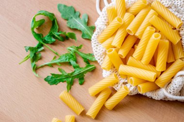 Çiğ pişmemiş Tortiglioni makarna makarna makarna beyaz kase ahşap arka plan fesleğen domates pesto sosu ev yapımı İtalyan yemeği tam buğday vegan spagetti sağlıklı bir yemek için.