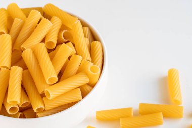 Çiğ pişmemiş Tortiglioni makarna makarna makarna beyaz kase ahşap arka plan fesleğen domates pesto sosu ev yapımı İtalyan yemeği tam buğday vegan spagetti sağlıklı bir yemek için.