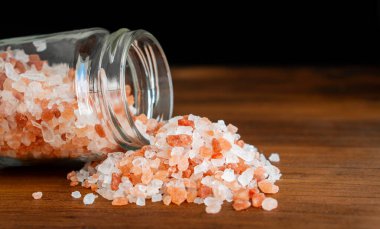 Pembe ve beyaz doğal Himalaya kristali dağları organik deniz tuzu tanecikleri öğütücü şişedeki malzemeler kırsal, siyah mutfak ahşap masa.