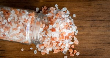 Pembe ve beyaz doğal Himalaya kristali dağları organik deniz tuzu tanecikleri öğütücü şişedeki malzemeler kırsal, siyah mutfak ahşap masa.