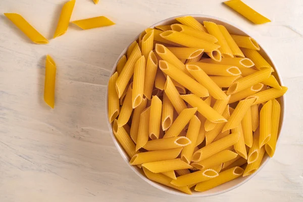 Rauwe Droge Ongekookte Penne Pasta Een Kom Witte Achtergrond Goed — Stockfoto