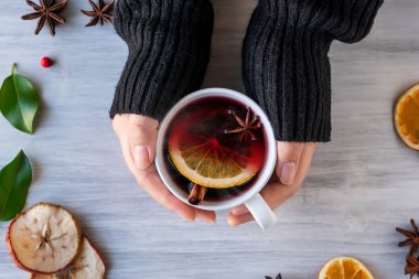 Alman geleneği, yeni yıl Noel pazarı yeni yıl festivali Gluhwein 'i elma portakallı turuncu bardakta sıcak tatlı kırmızı şarap ile baharatlı turunçgil aromalı anason yıldızı anason kadın elini tutuyor.