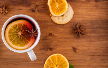 Alman geleneği, yeni yıl Noel pazarı yeni yıl festivali Gluhwein 'i elma portakallı turuncu bardakta sıcak tatlı kırmızı şarap ile baharatlı turunçgil aromalı anason yıldızı anason kadın elini tutuyor.