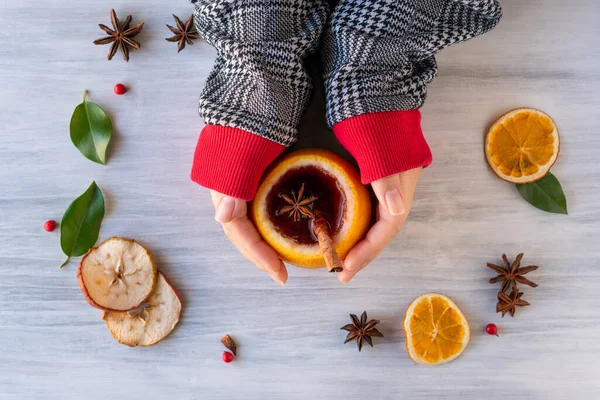 German tradition winter Christmas market new year holidays festival drink Gluhwein Mulled sweet hot warm red Wine in apple orange mug with spices citrus aromatic cinnamon star anise woman hand hold