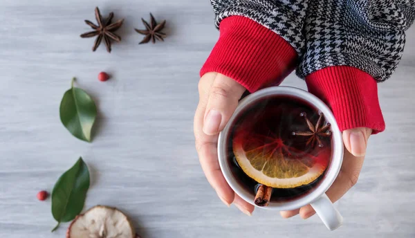 German tradition winter Christmas market new year holidays festival drink Gluhwein Mulled sweet hot warm red Wine in apple orange mug with spices citrus aromatic cinnamon star anise woman hand hold
