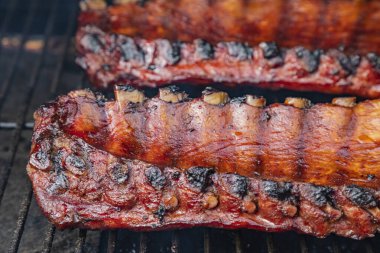 Barbekü soslu ve ızgarada pişen iki dilim bbq pirzolasının yan görüntüsünü kapat.