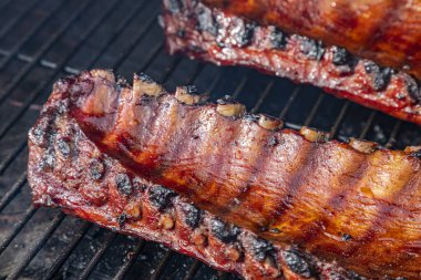 Barbekü soslu, ızgara tabağında pişen iki raf bbq pirzolasının yan görüntüsünü kapat.