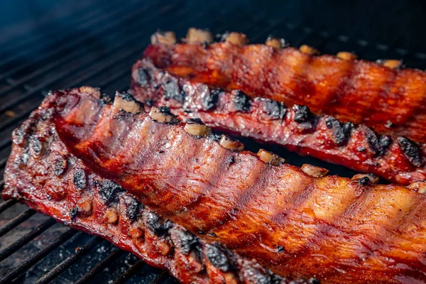 Yandan 2 sıra bbq pirzolası. Izgarada barbekü sosu pişiyor. İçicinin görünür dumanıyla çevrili.