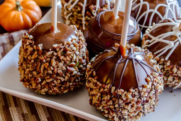 Mão mergulhado maçãs de caramelo com nozes e chocolate — Fotografia de Stock