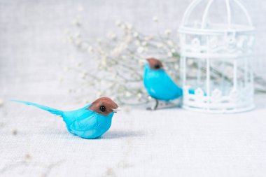 Oyuncak kuşlar, çiçekler ve kafeslerden oluşan bir kartpostal.