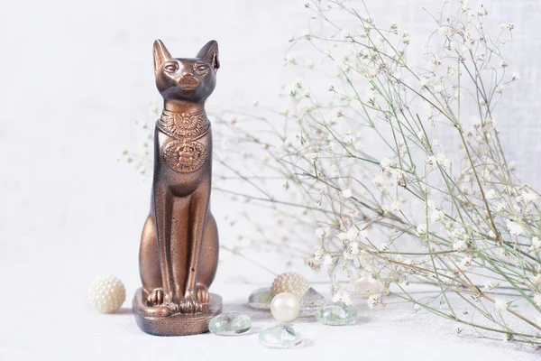 egypt cat statuette and flowers on light background