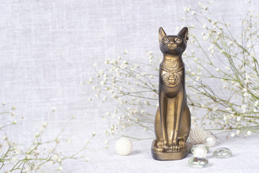 egypt cat statuette and flowers on light background