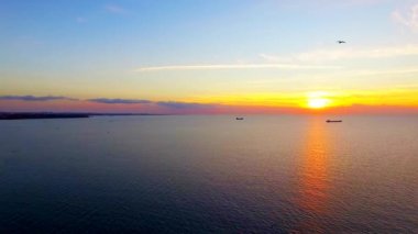 Gün batımında deniz üzerinde uçan kuşlar