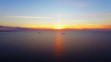 Gün batımında denizde yüzen iki tekne