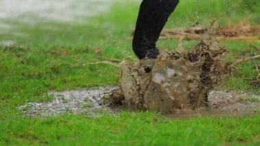 Mutlu çocuk içinde çamurlu su birikintisi atlama