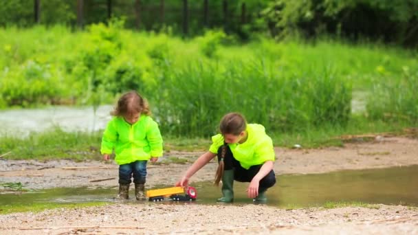 Szczęśliwe dzieci bawią się w Puddle na zielonej łące — Wideo stockowe