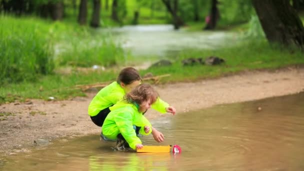 Lindos niños jugando coches en enorme charco en el parque — Vídeo de stock