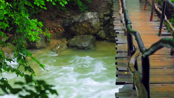 Puente de madera colgando sobre el río áspero — Vídeo de stock