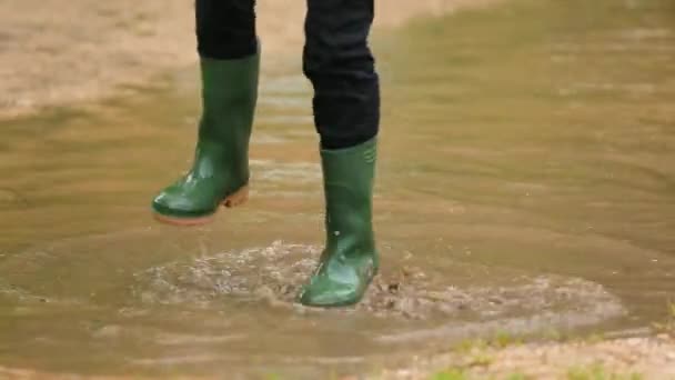 Glückliches Kind springt in riesige Pfütze — Stockvideo