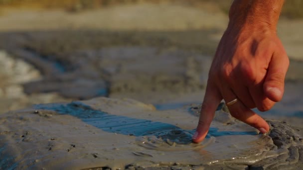 Людська рука торкається вулканічного бруду — стокове відео