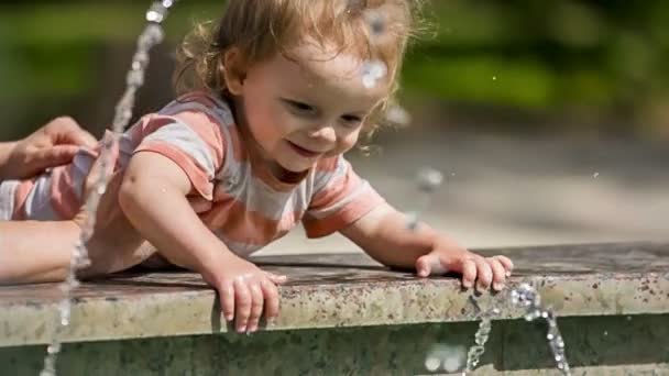 Мальчик трогает воду в фонтане — стоковое видео