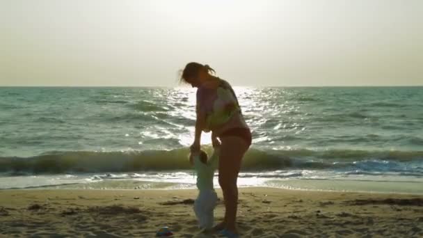 해변에서 그녀의 작은 아기를 회전 하는 행복한 어머니 — 비디오