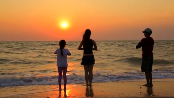 Três crianças fazendo exercícios de ioga na praia ao pôr do sol — Vídeo de Stock