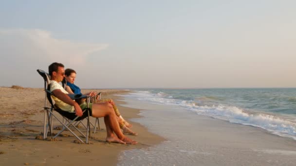 Romantiskt par koppla av på solstolar på stranden — Stockvideo