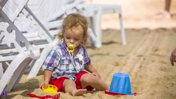 Маленький мальчик играет в песок — стоковое видео