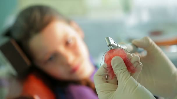 Девушка смотрит, как ортодонт исправляет брекеты для кривых зубов — стоковое видео
