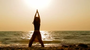 Young Woman Practicing Yoga On Sandy Beach At Sunset