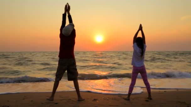 Boy And Girl Making Exercises On The Beach At Sunset — Stok video