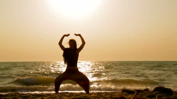 Junge Frau macht Yoga am Sandstrand bei Sonnenuntergang — Stockvideo