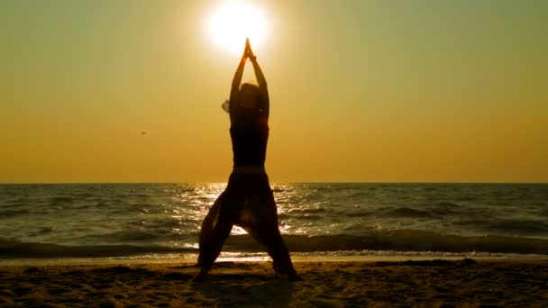 junge Frau praktiziert Yoga am Strand bei Sonnenuntergang