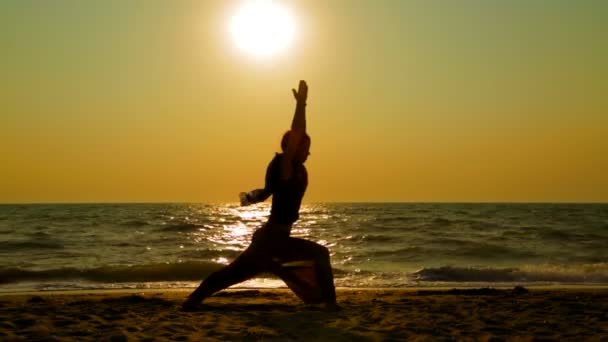 Mujer practicando yoga en la playa al atardecer — Vídeos de Stock