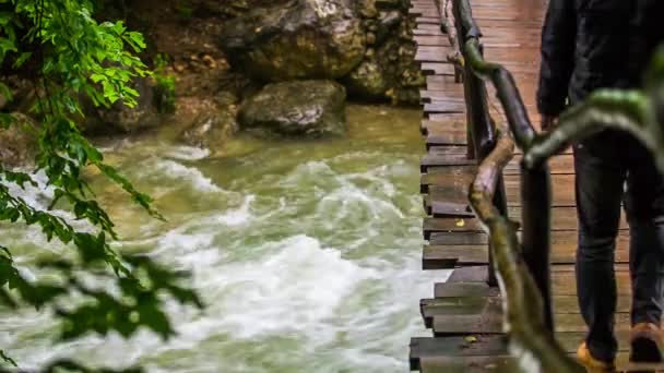 Uomo che cammina sul ponte appeso sopra il fiume ruvido — Video Stock