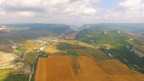 Vista de ojos de aves de la localidad de Hilly y campo de cosecha — Vídeos de Stock