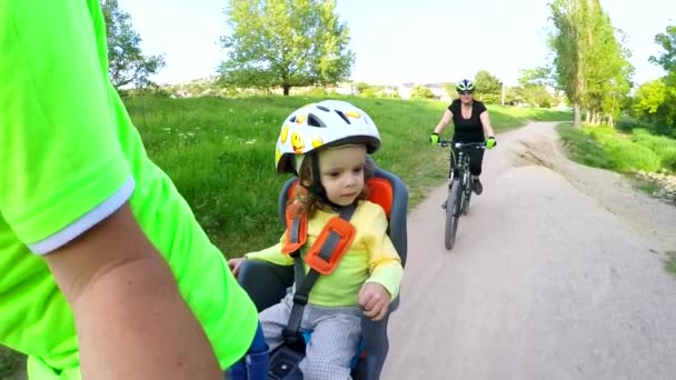 Bambino piccolo sul sedile posteriore della bici che si gode il viaggio insieme ai genitori in Green Park — Video Stock