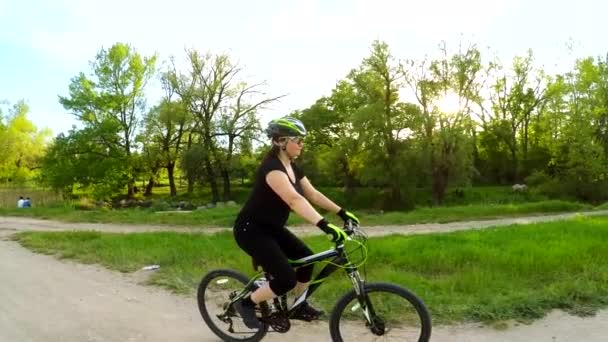 緑豊かな公園で自転車に乗って若い女性 — ストック動画