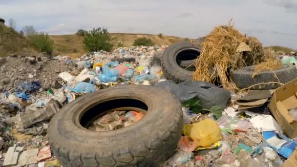 Ruedas de coche entre la basura vertida en un montón en el vertedero en Ucrania — Vídeos de Stock