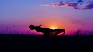 Gün batımında Yoga Asanas uygulamak bir genç kız silüeti